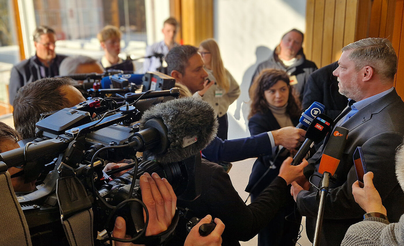 Heiko Teggatz spricht in Mikrofone einer Journalistentraube