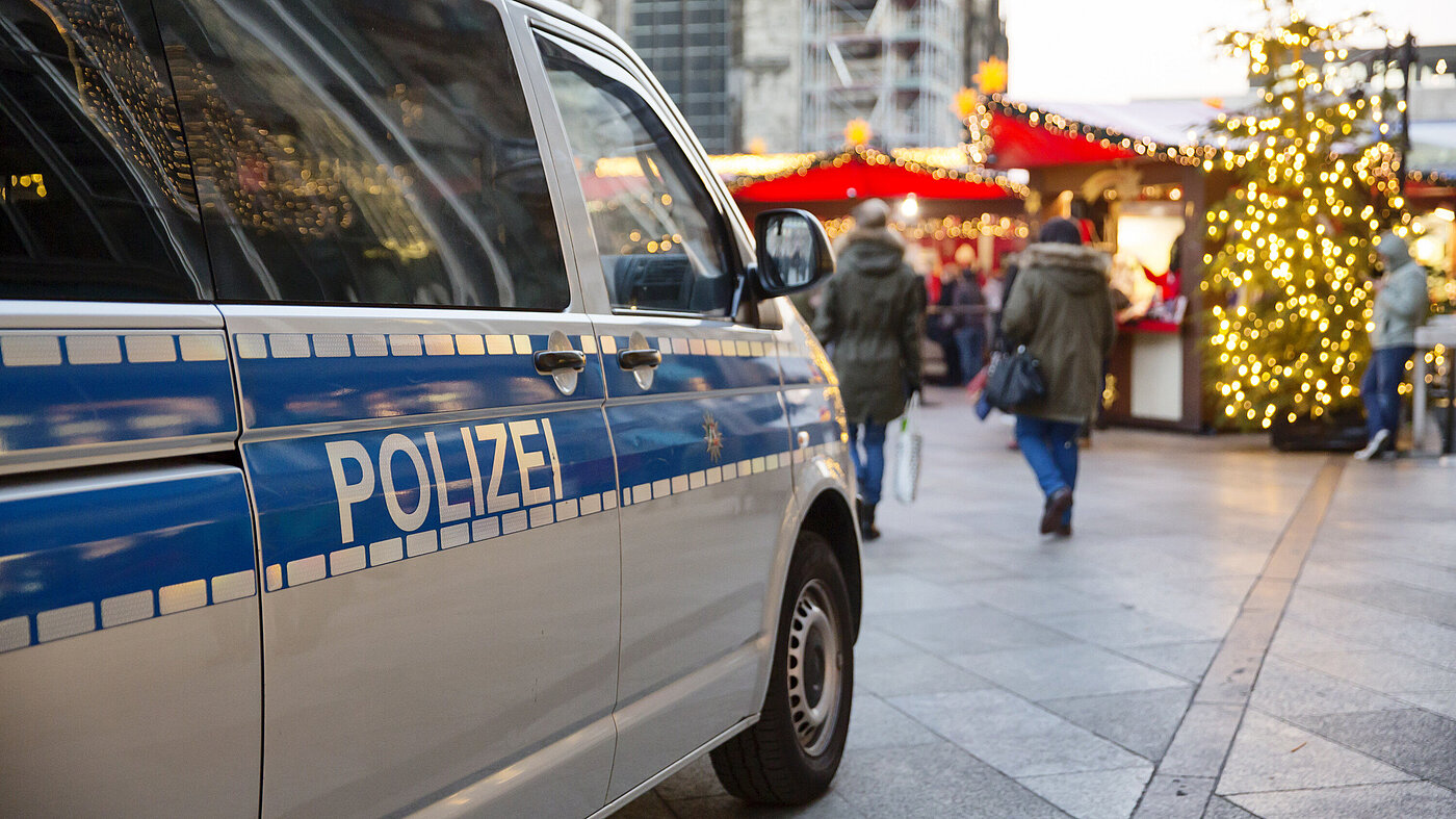 Einsatzwagen der Polizei parkt vor einem weihnachtsmarkt