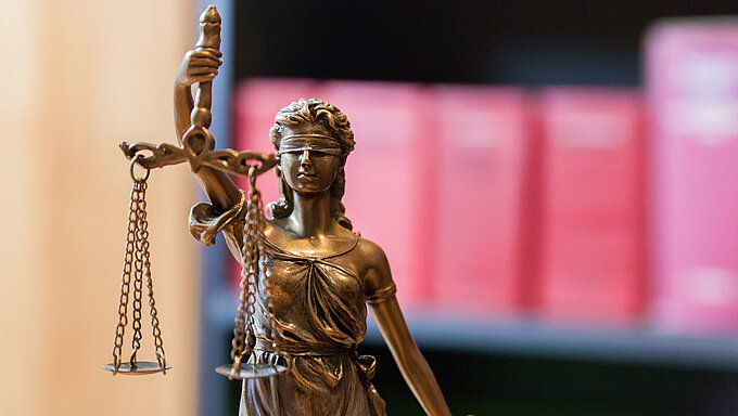 Justitia vor Bücherregal mit Gesetzbüchern
