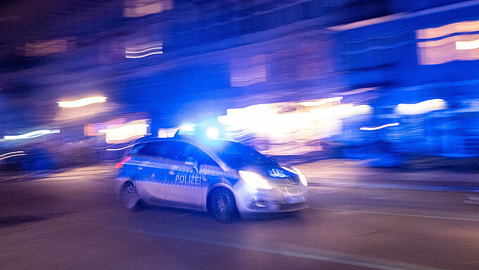 Patrol car of the Berlin police drives with blue lights to a mission through Oderberger Straße in Berlin-Prenzlauer Berg on New Year's Eve. Polizeiwagen in Berlin nachts auf Streife